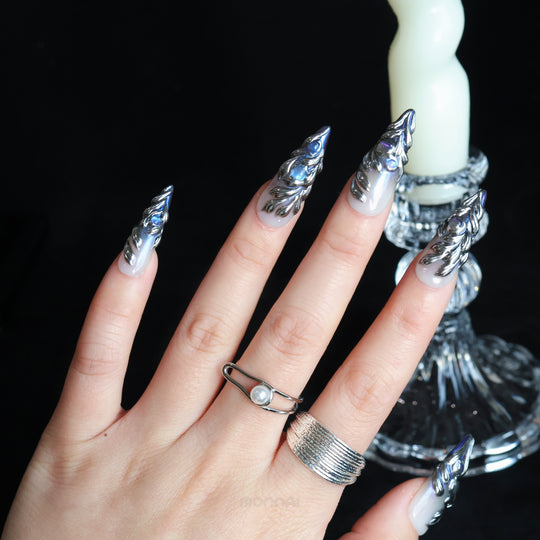 Silver Dreams press-on nails worn on hand, with icy chrome feather textures and iridescent silver accents.