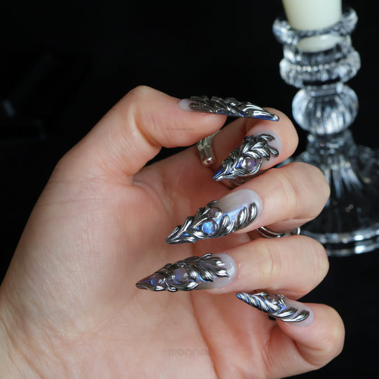 Silver Dreams press-on nails worn on hand, with chrome feather-like textures and cool iridescent accents.