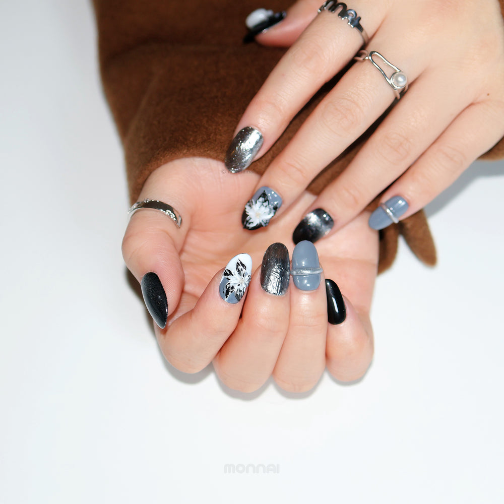 Silver Eclipse press-on nails worn on hands, moody sleek black, grey and chrome floral designs with glossy accents