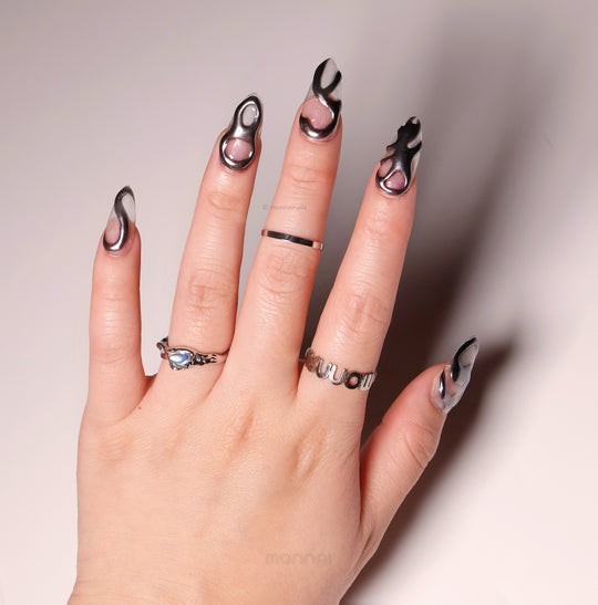 Silver Mystic Flow press-on nails worn on hand, sculptural liquid chrome silver lines with glossy futuristic contrast.
