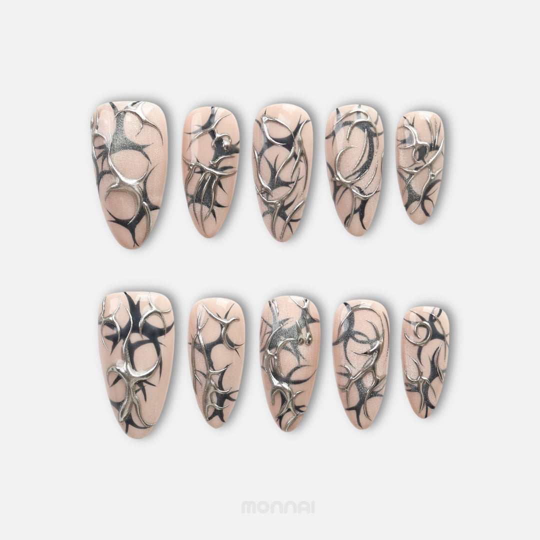 Silver Veins press on nails with black thorn patterns and raised silver chrome over nude shimmer
