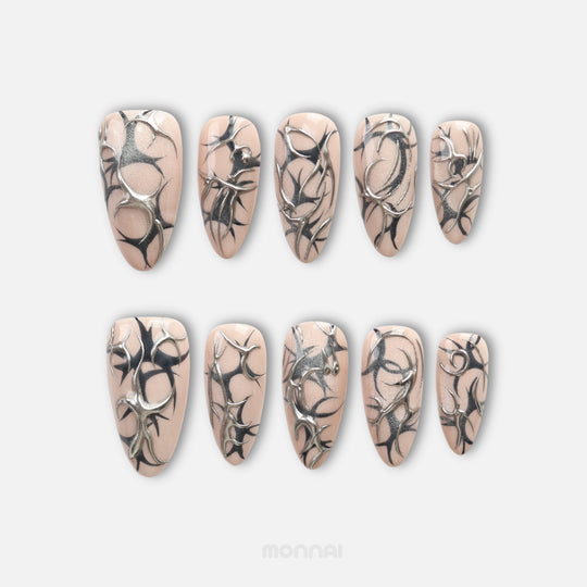 Silver Veins press on nails with black thorn patterns and raised silver chrome over nude shimmer
