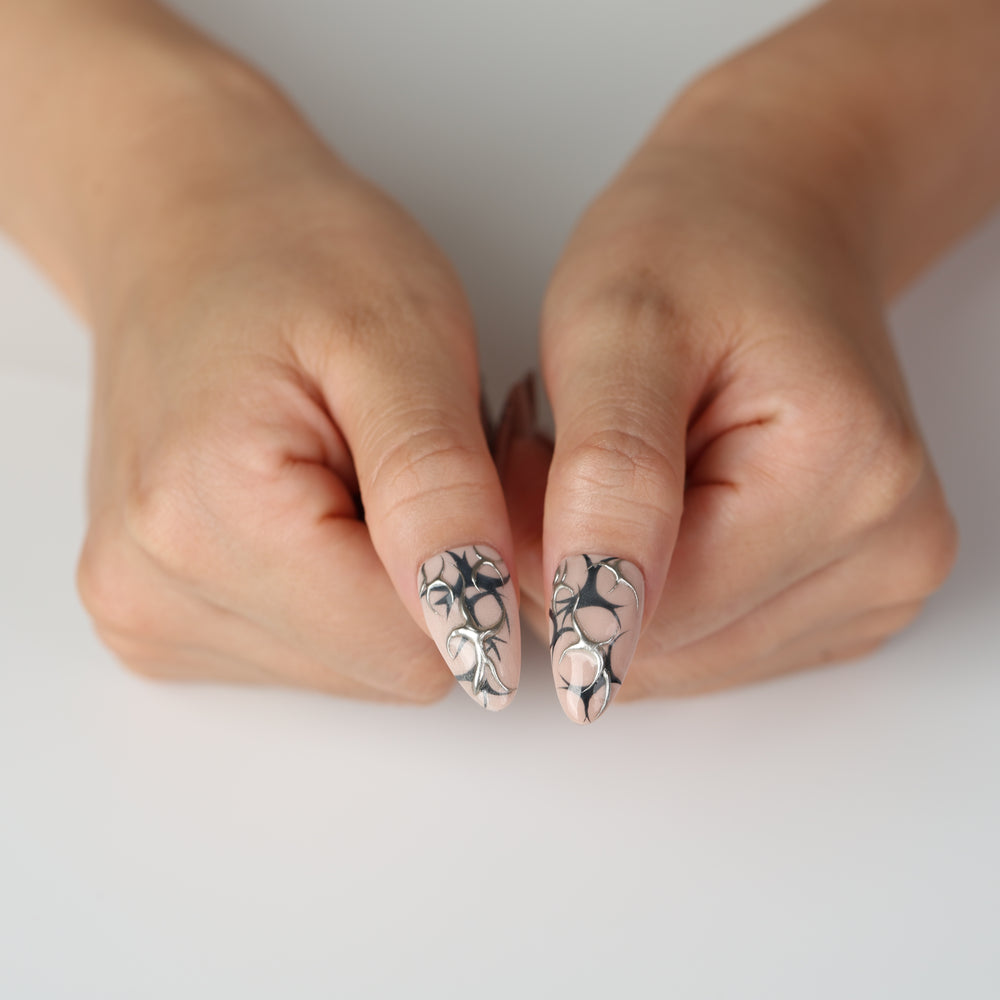 Silver Veins press on nails with black thorn patterns and raised silver chrome details on a nude base