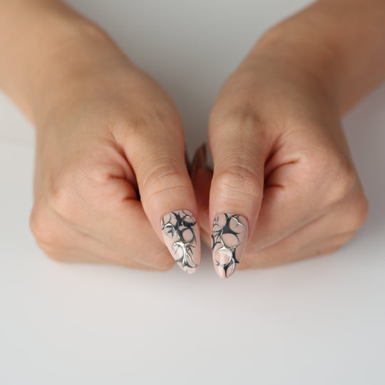 Silver Veins press on nails with black thorn patterns and raised silver chrome details on a nude base