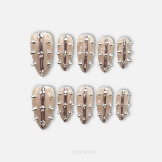 Silver Spine press-on nails laid out with nude base, silver spikes, and raised metallic lines.