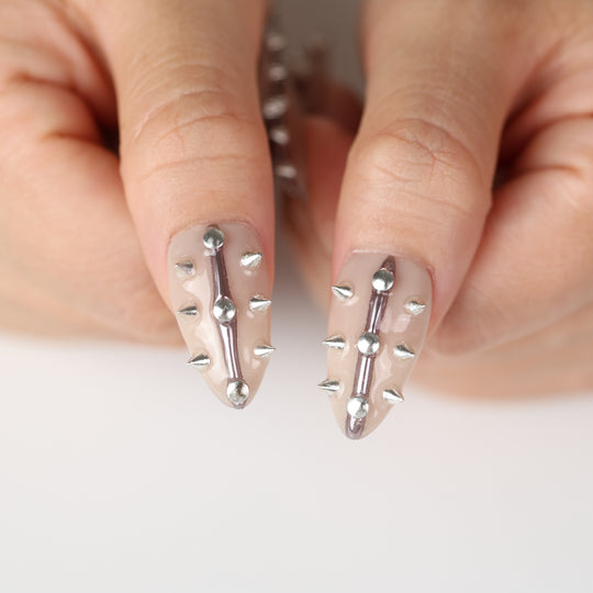 Silver Spine press-on nails on hand, nude base with silver spikes, studs, and raised metallic lines