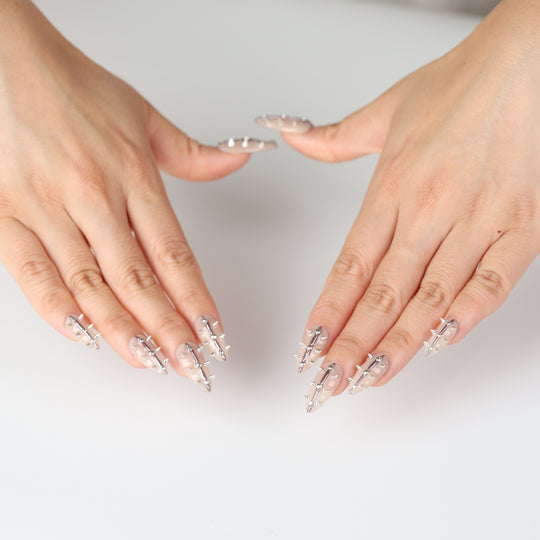 Silver Spine press-on nails on hands, nude base with silver spikes and metallic lines
