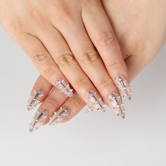 Silver Spine press-on nails on hand with nude base, silver spikes, studs, and metallic lines