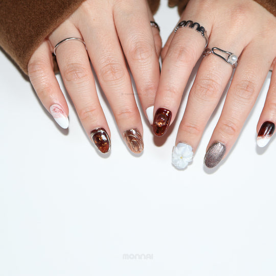 Smoky Quartz press-on nails worn on hands, with moody brown marble accents, white flower detail, and silver glitter.