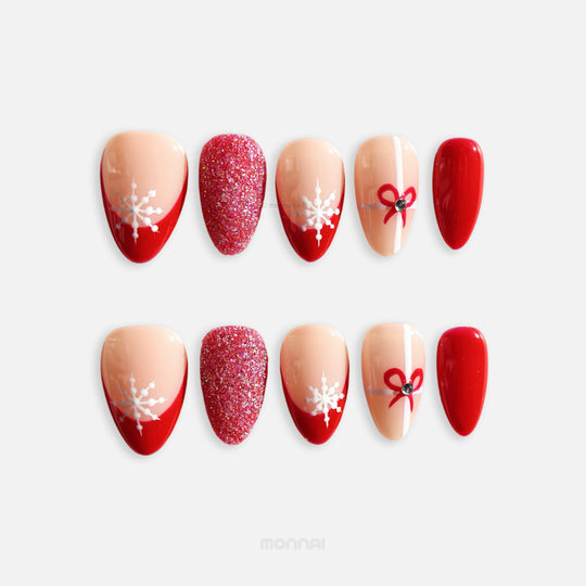 Snowflake Gift Christmas-themed press-on nails laid out, with red French tips, snowflake art, glitter accent, and ribbon detail.