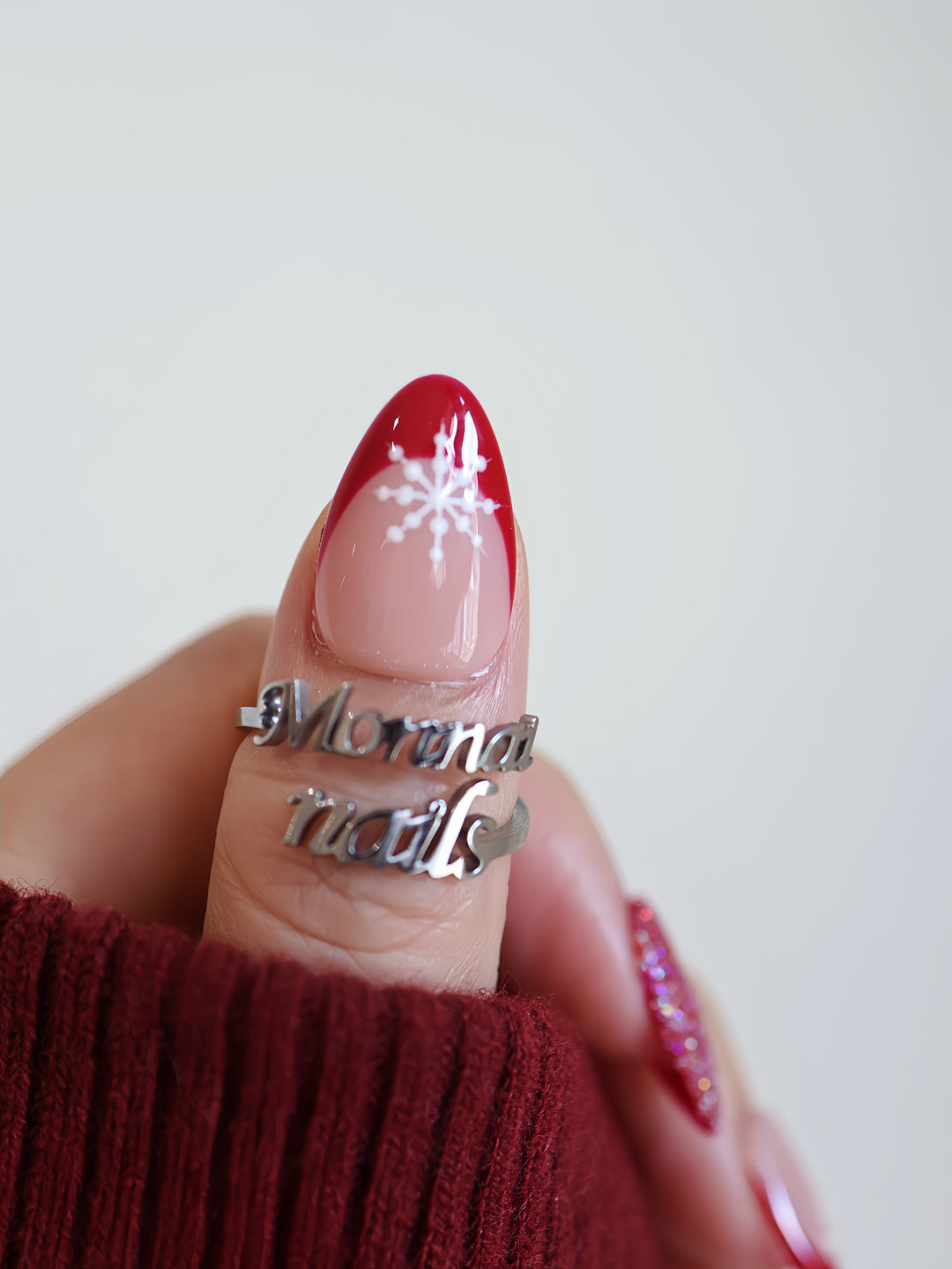 Snowflake Gift Christmas-themed press-on nails worn on hand, showing red French tip and white snowflake detail