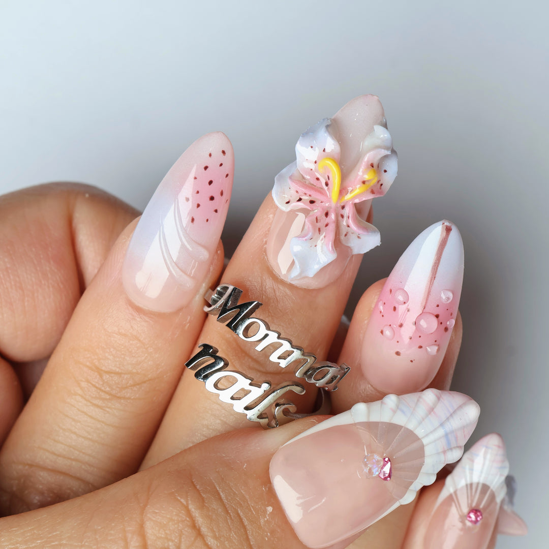 Somewhere in Time press-on nails worn on hand, showing botanical 3D orchids and shell-textured French tips in soft purple ombre.