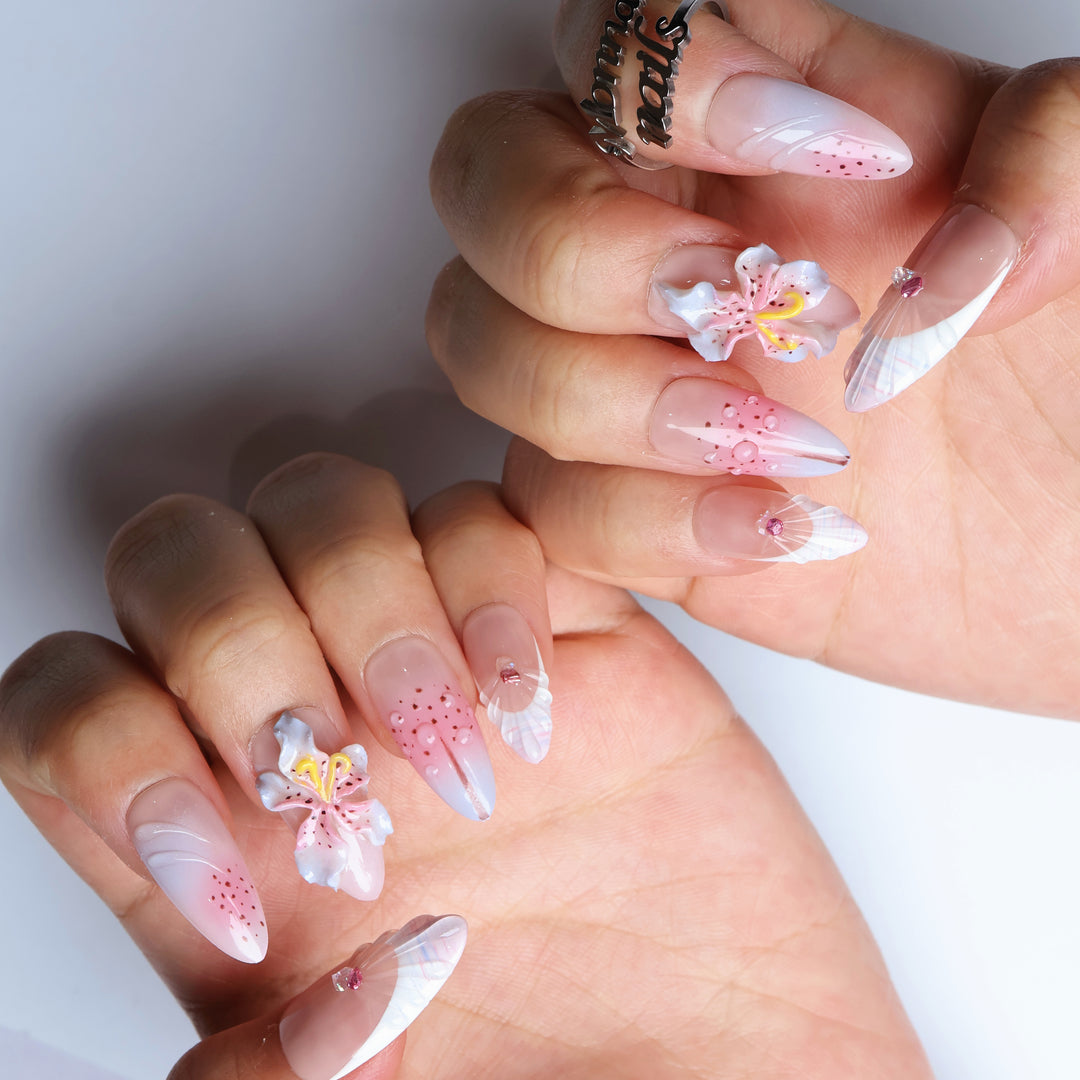 Somewhere in Time press-on nails worn on hands, showing botanical 3D orchids, soft purple ombre, shell French tips and jewels.