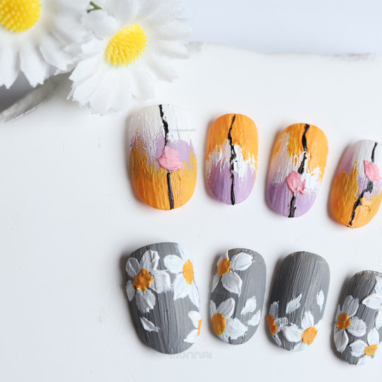 Spring on Canvas press-on nails laid out in textured grey and orange floral designs with lilac accents.