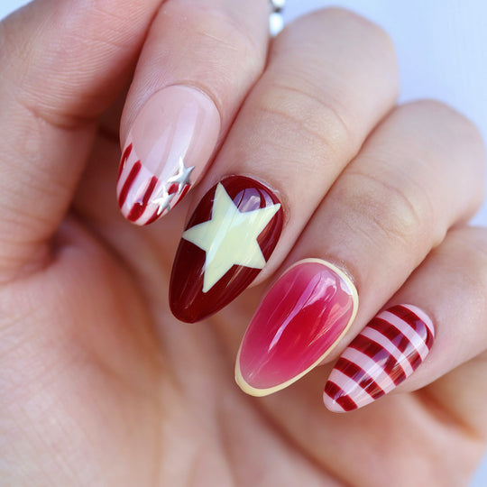 Star Parade press-on nails worn on hand, showing red aura gradients, butter yellow star and striped accents.