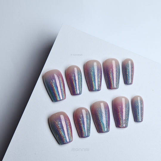 Stardust press-on nails with nude bases and pink-blue glitter ombré, shown laid out in two rows.