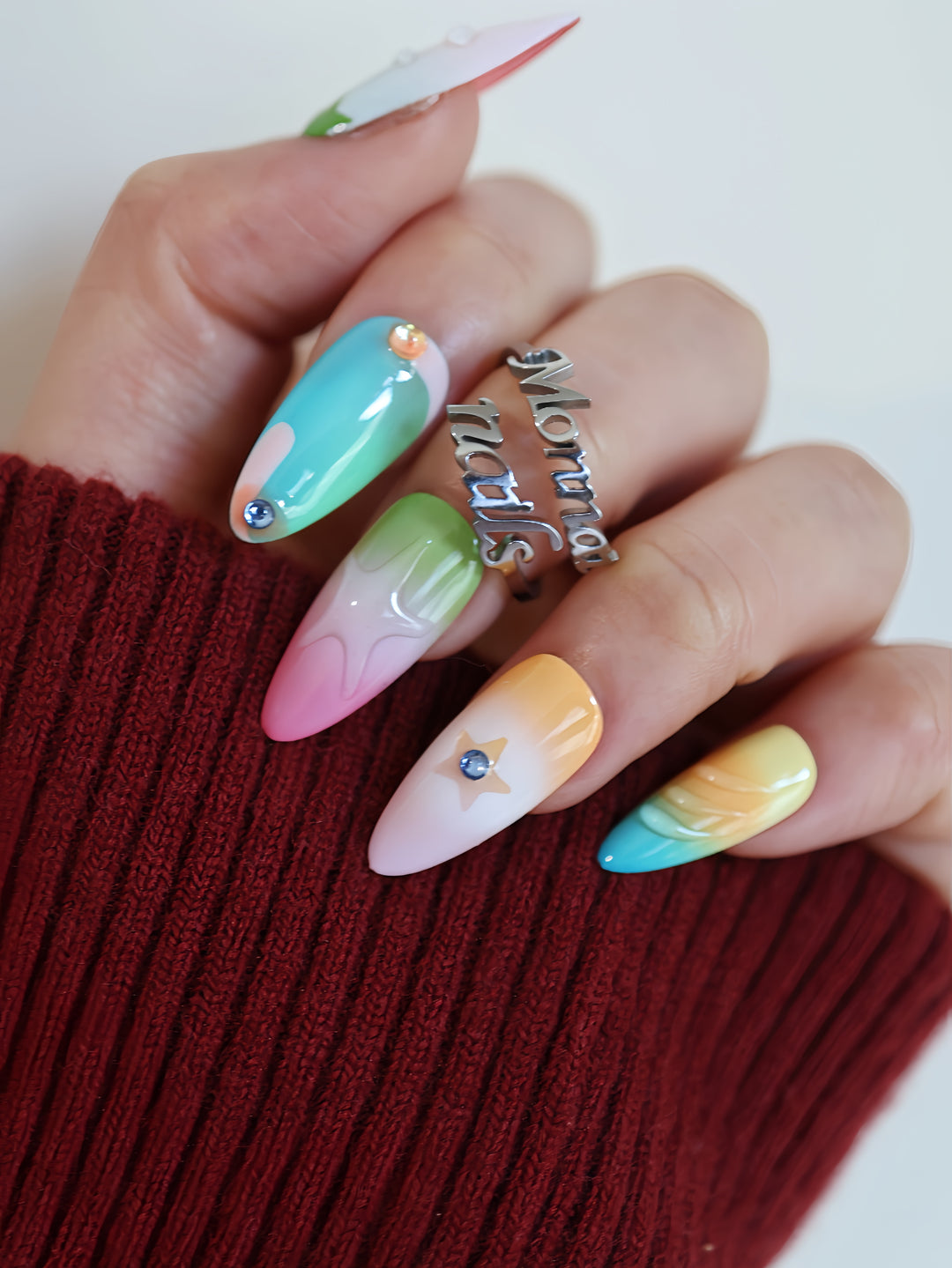 Starlight Pastels press-on nails worn on hand, with mint, pink, yellow and lilac glossy star accents