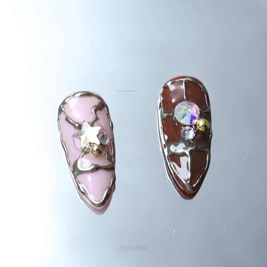 Starlit Glow press-on nails laid out in close-up, with retro playful pink and brown tones, metallic accents, and star crystal details.