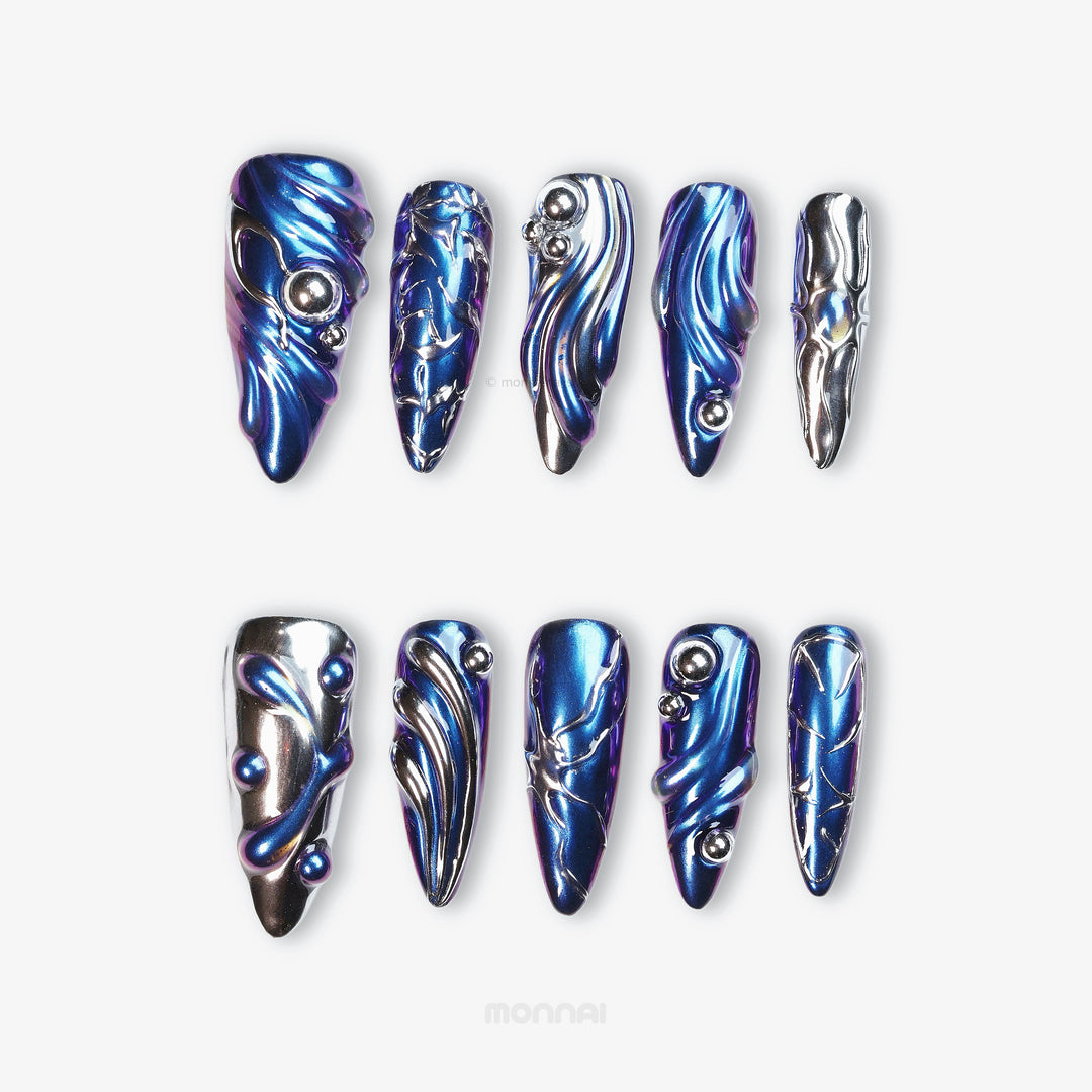 Stellar Ripples press-on nails laid out in close-up, with electric blue chrome, silver metallic detailing, and wave-like futuristic sculpted lines.
