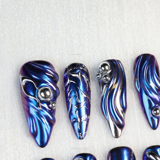 Stellar Ripples press-on nails with electric blue chrome and silver metallic wave details, shown laid out in close-up