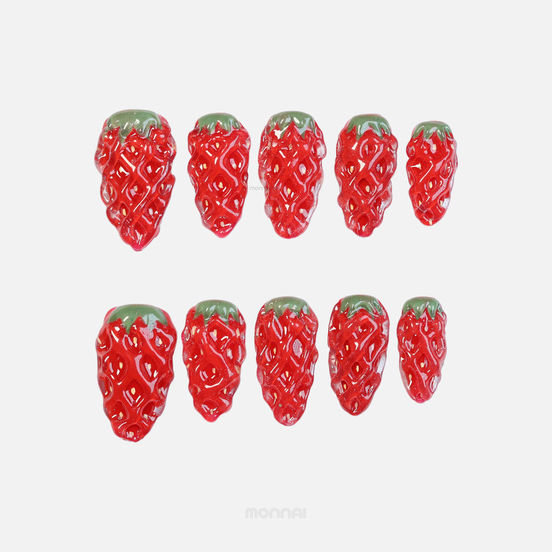 Strawberry Delight press-on nails shown in close-up, with ripe summer strawberry texture, red gloss and green stems.