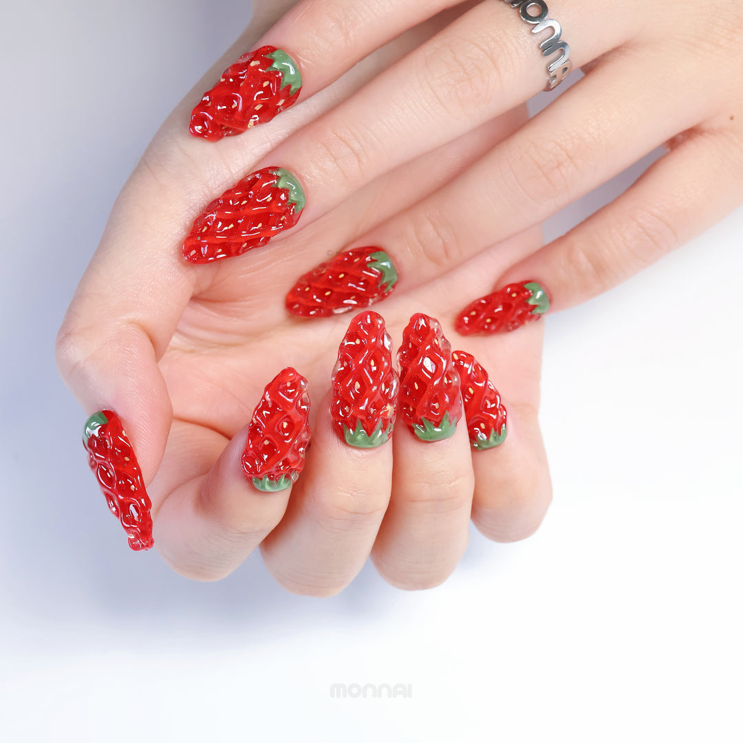 Strawberry Delight press-on nails on hand, hyper-realistic red strawberry 3D texture with green leafy tips