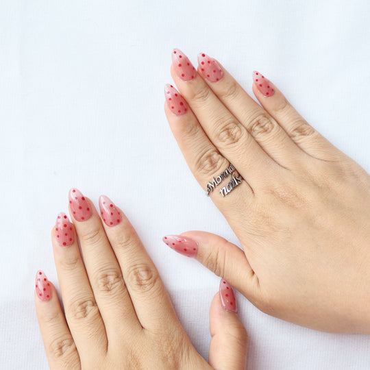 Strawberry Mousse press-on nails worn on hands, showing nude pink jelly nails with red polka dots and a glossy finish.