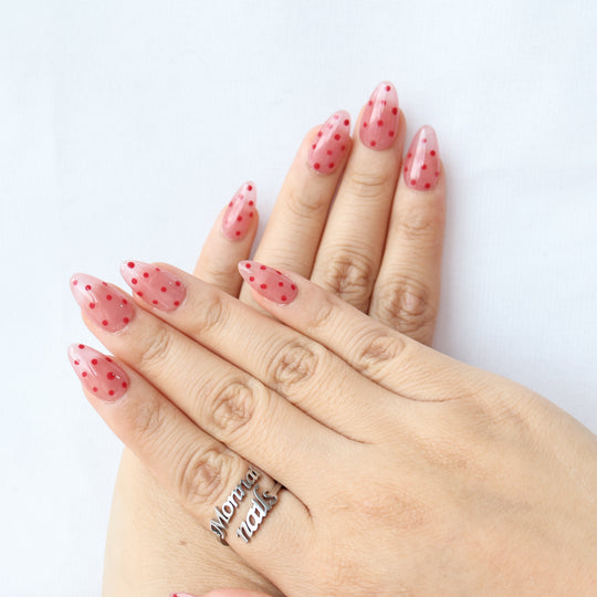 Strawberry Mousse press-on nails on hands, nude pink jelly base with red polka dots and glossy finish