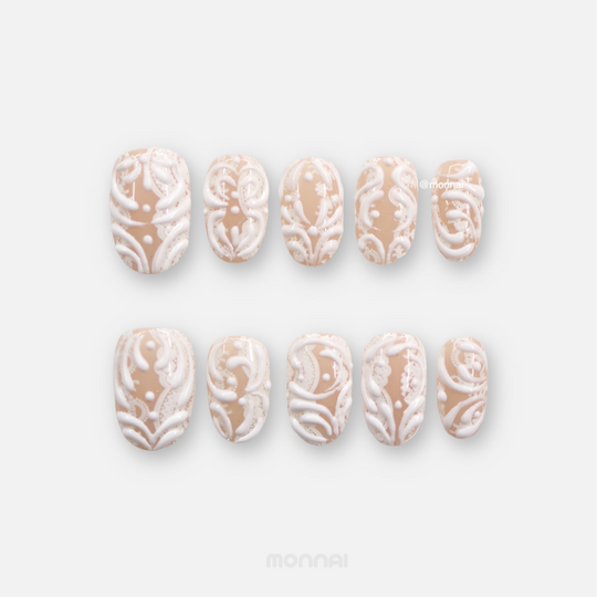 Sugar Carving press-on nails set with sheer nude base, white 3D swirls, and lace details laid out on white