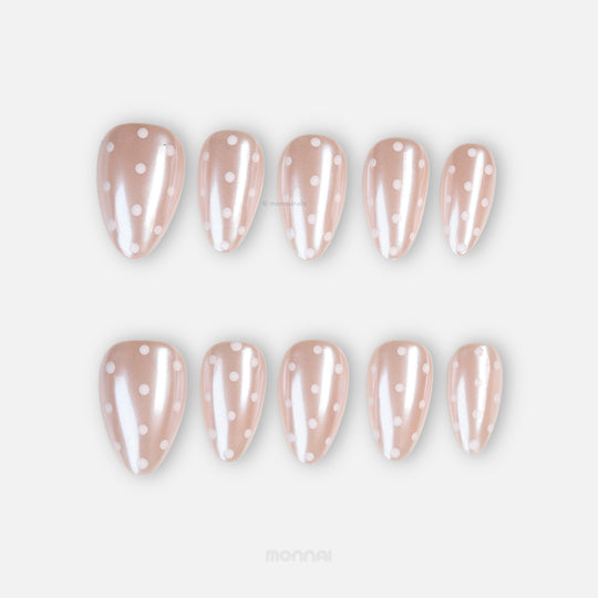 Sugar Glaze press-on nails laid out in sheer champagne pink with white polka dots and pearlescent shimmer