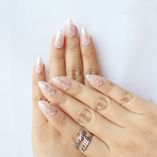 Sugar Glaze press-on nails shown on hands, sheer champagne pink with white polka dots and pearlescent shimmer.