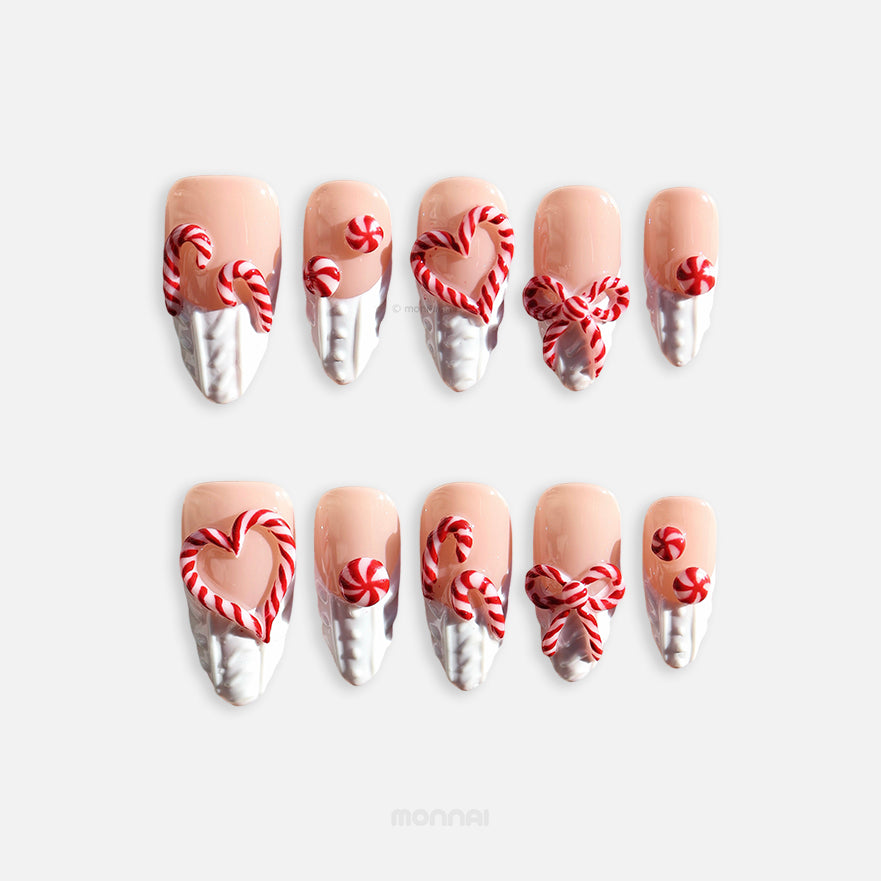 Sugar Kiss press-on nails laid out with nude, white knit texture, and red candy cane heart and bow designs