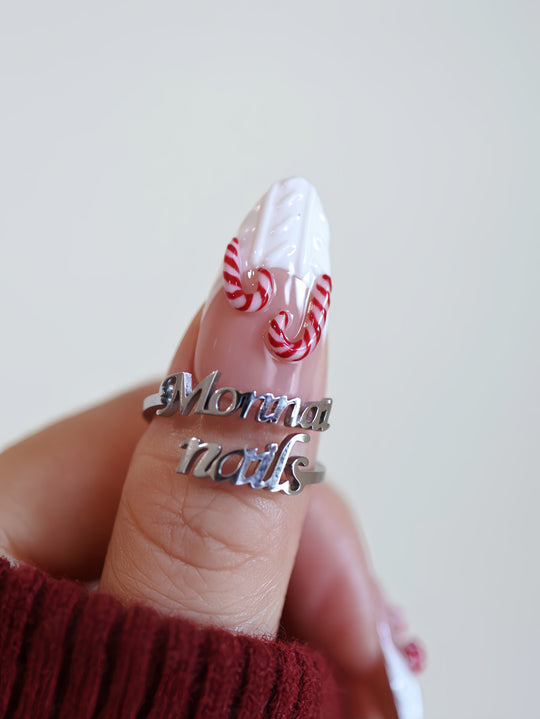 Sugar Kiss press-on nails on hand with white 3D knit texture and red candy cane swirl details