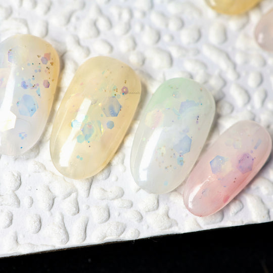 Sugar Sparkle press-on nails in pastel yellow, mint, pink and white with airy foil-like accents, shown in close-up.