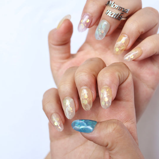 Sugar Sparkle press-on nails on hand, sheer pastel shimmer with scattered foil accents and a soft dreamy glow