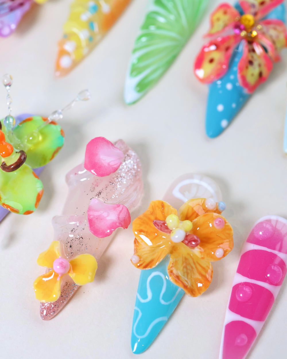 Summer Garden Party press-on nails laid out in bright tropical colors with 3D flowers, citrus details, and glossy finishes