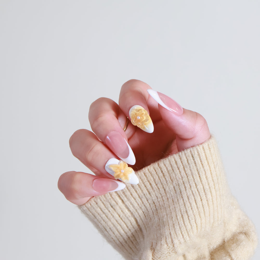 Sunflower Bliss press-on nails on hand with milky white French tips and honey amber 3D floral accents