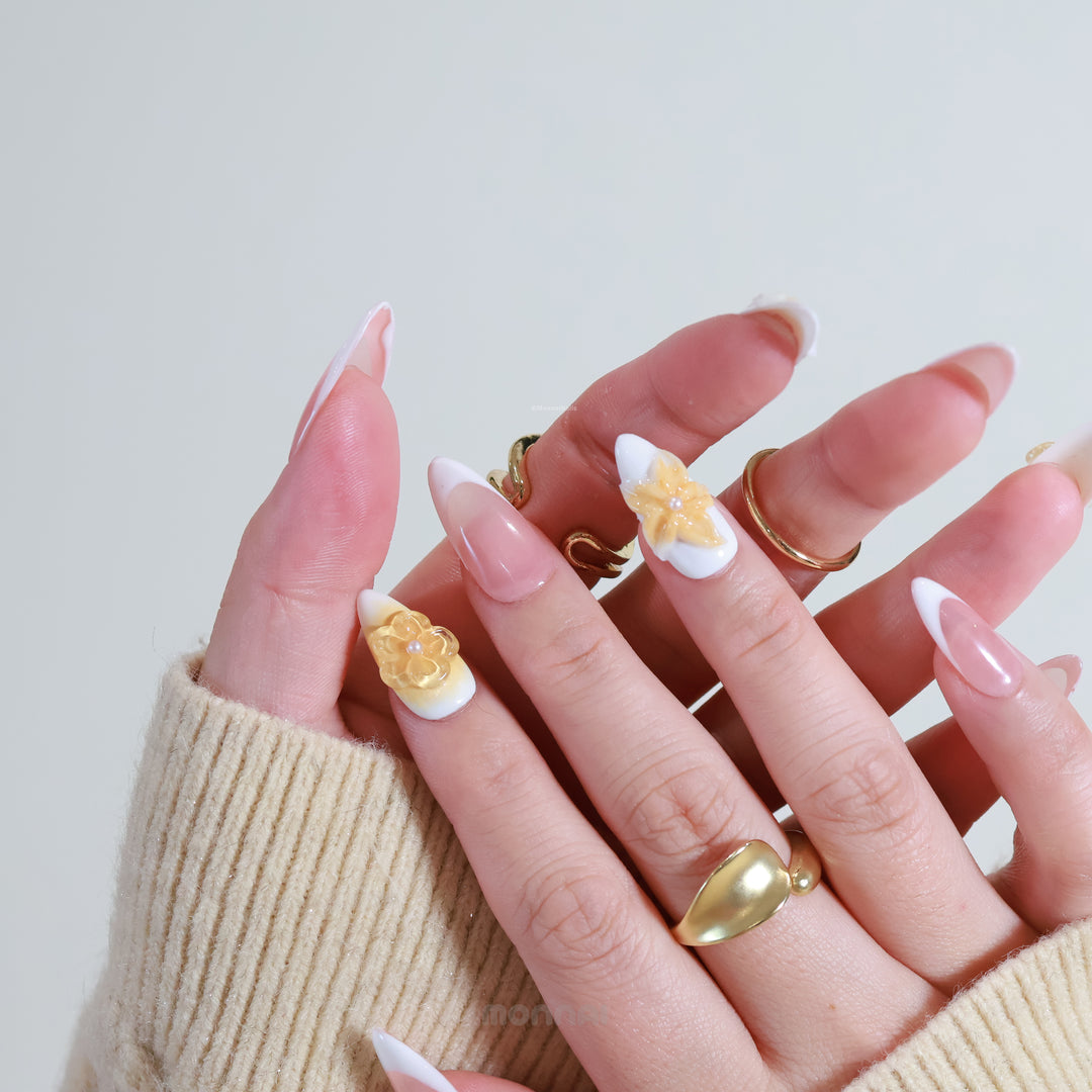Sunflower Bliss press-on nails on hands, with milky white French tips and honey amber 3D floral accents.
