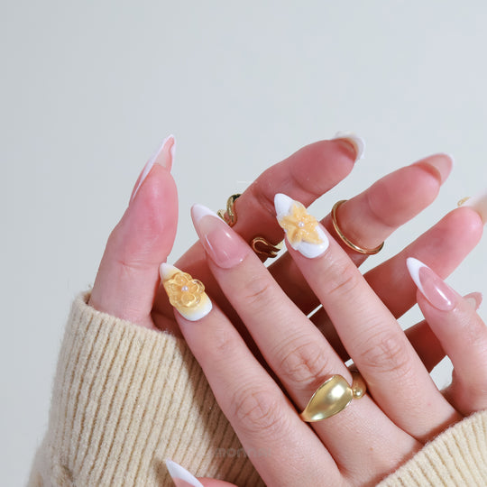Sunflower Bliss press-on nails on hands, with milky white French tips and honey amber 3D floral accents.