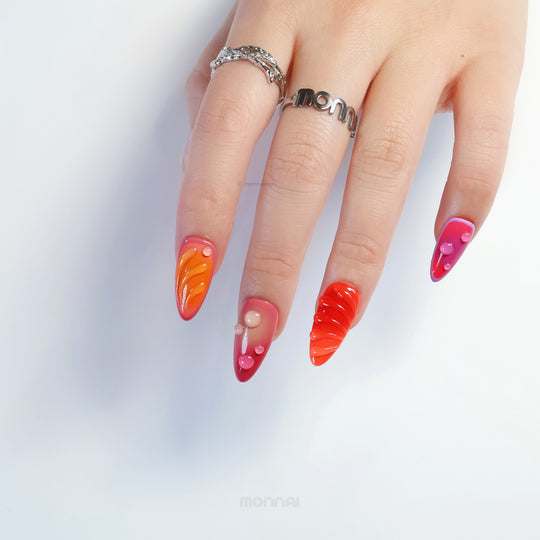 Sunset Flow press-on nails on hand, bold playful summer design in vivid red and purple with glossy bubble accents