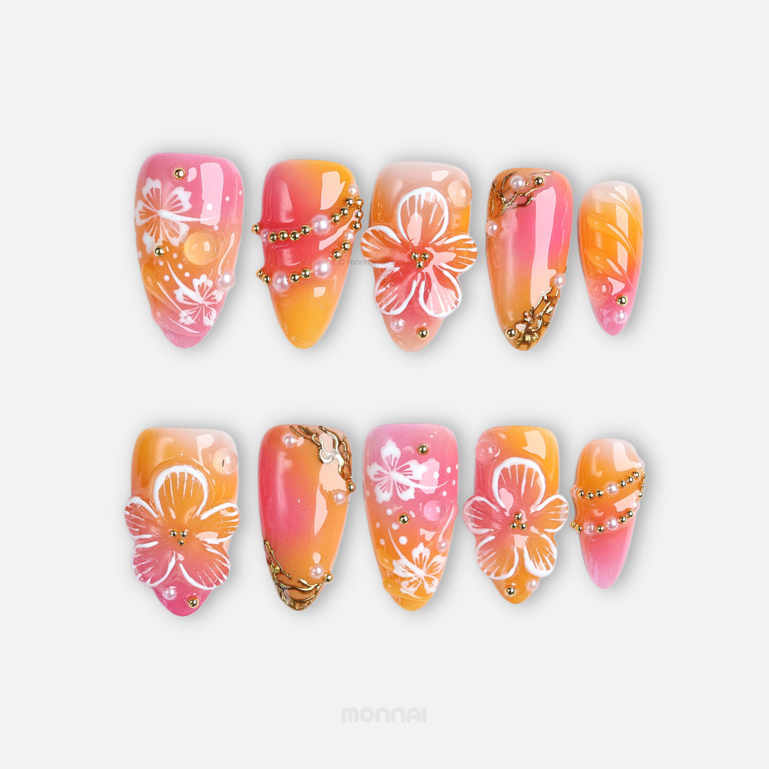 Sunset Hibiscus press-on nails laid out with glossy pink and orange ombré, hibiscus florals, and gold accents