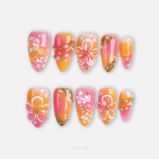 Sunset Hibiscus press-on nails laid out with glossy pink and orange ombré, hibiscus florals, and gold accents