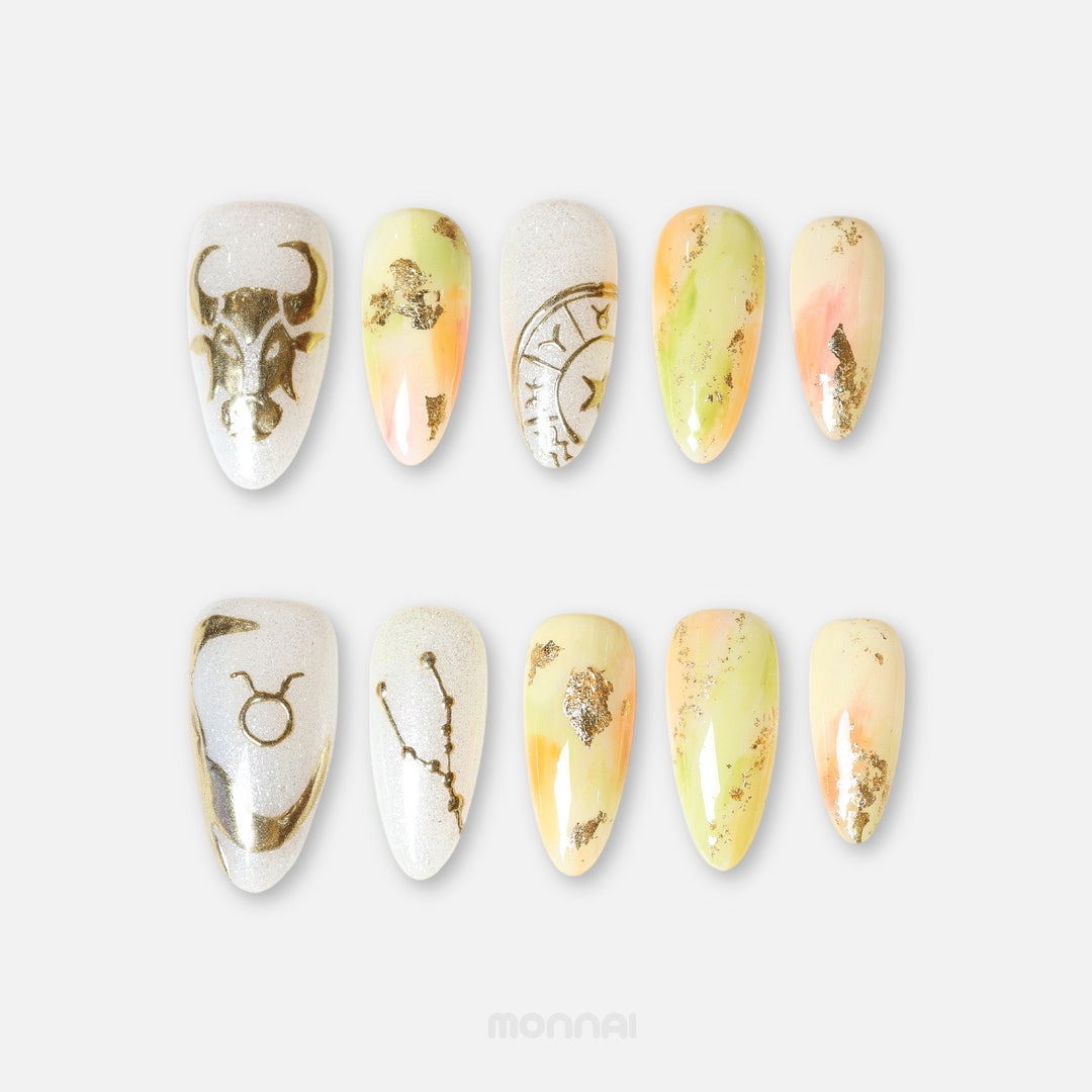 Taurus press on nails from the Zodiac Collection, featuring soft ivory and pastel tones, gold foil, bull motifs and celestial zodiac details.