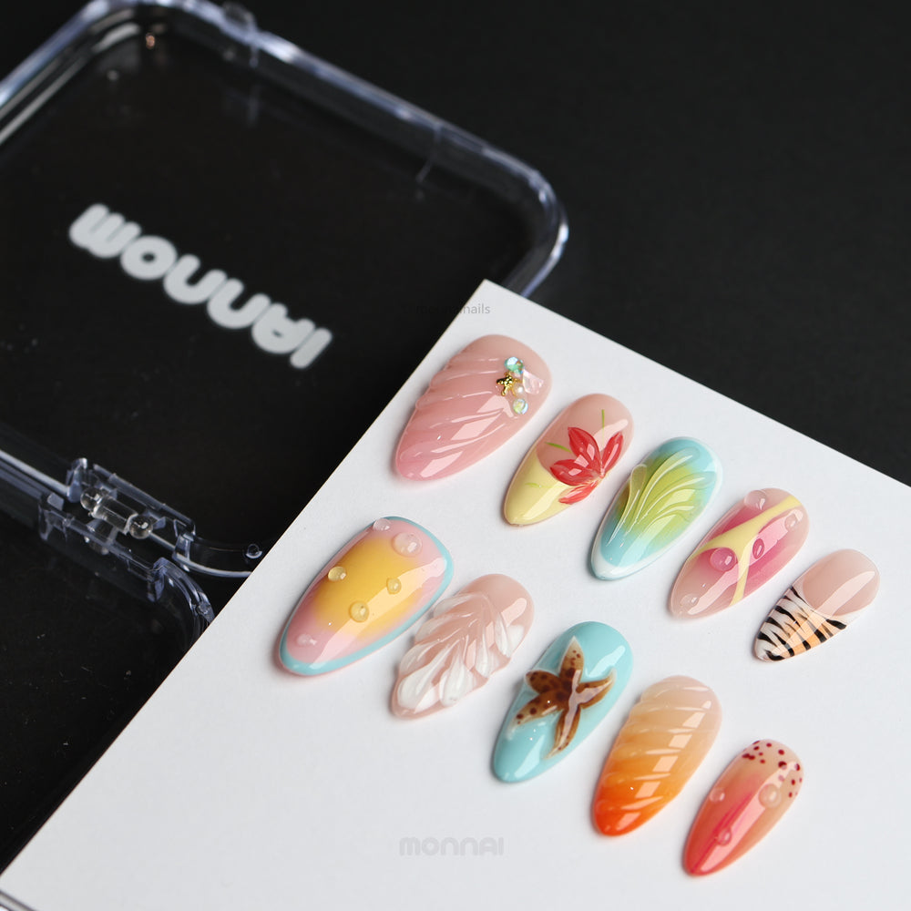The Beach press-on nails laid out, showing seafoam blue and sunset gradients with starfish, shell textures, and water droplets.