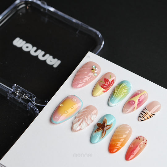 The Beach press-on nails laid out, showing seafoam blue and sunset gradients with starfish, shell textures, and water droplets.