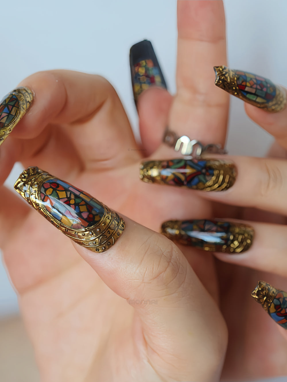 The Fifth Window press-on nails worn on hands, with cathedral-inspired stained-glass motifs and sculpted bronze frames.