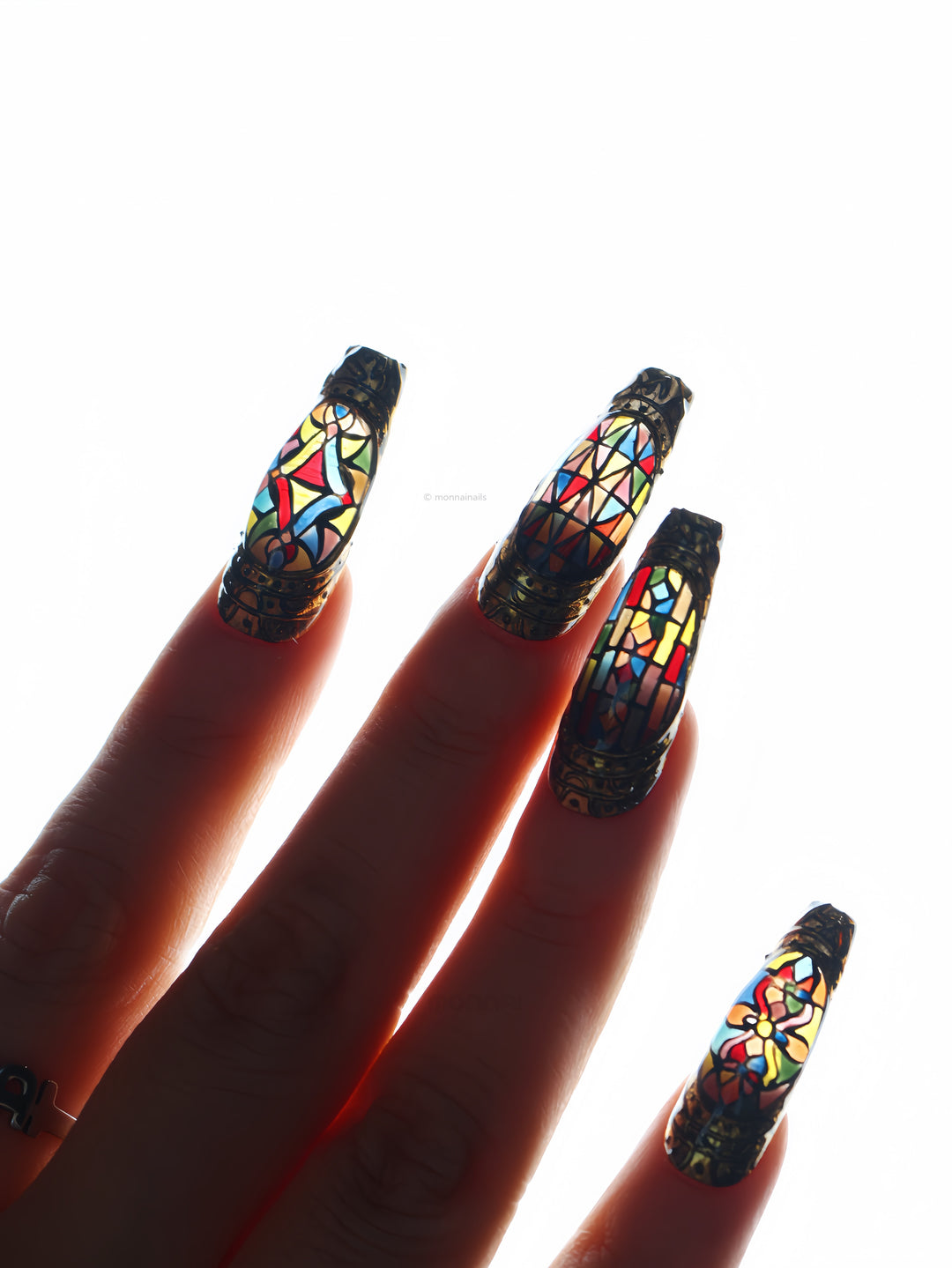 The Fifth Window press-on nails worn on hand, stained-glass motifs in sculpted bronze frames with antique 3D texture