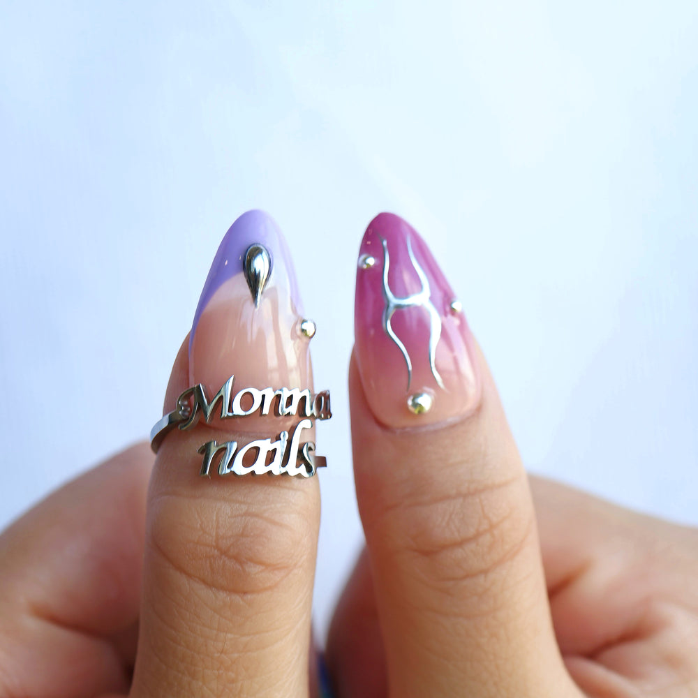 Toxic press-on nails worn on hands, with milky white, lavender and bold red chrome accents and silver details.