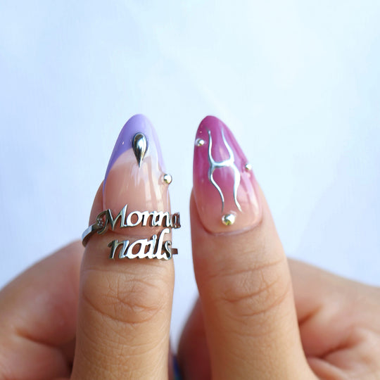 Toxic press-on nails worn on hands, with milky white, lavender and bold red chrome accents and silver details.