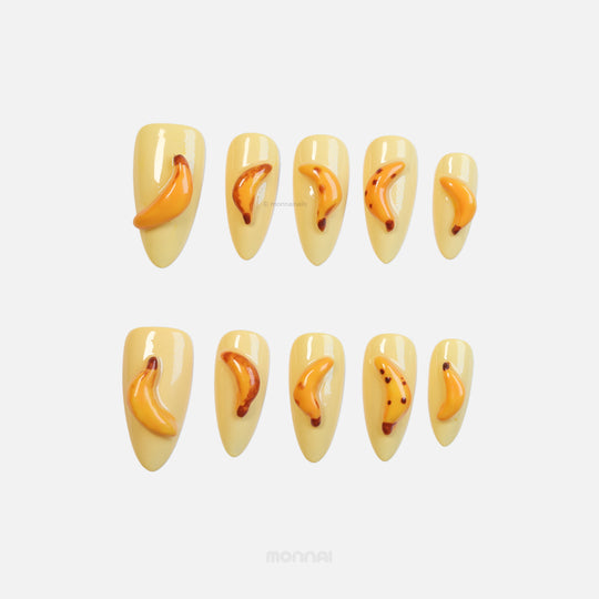 Tropical Banana press-on nails with pale yellow base and glossy 3D banana accents laid out in two rows.
